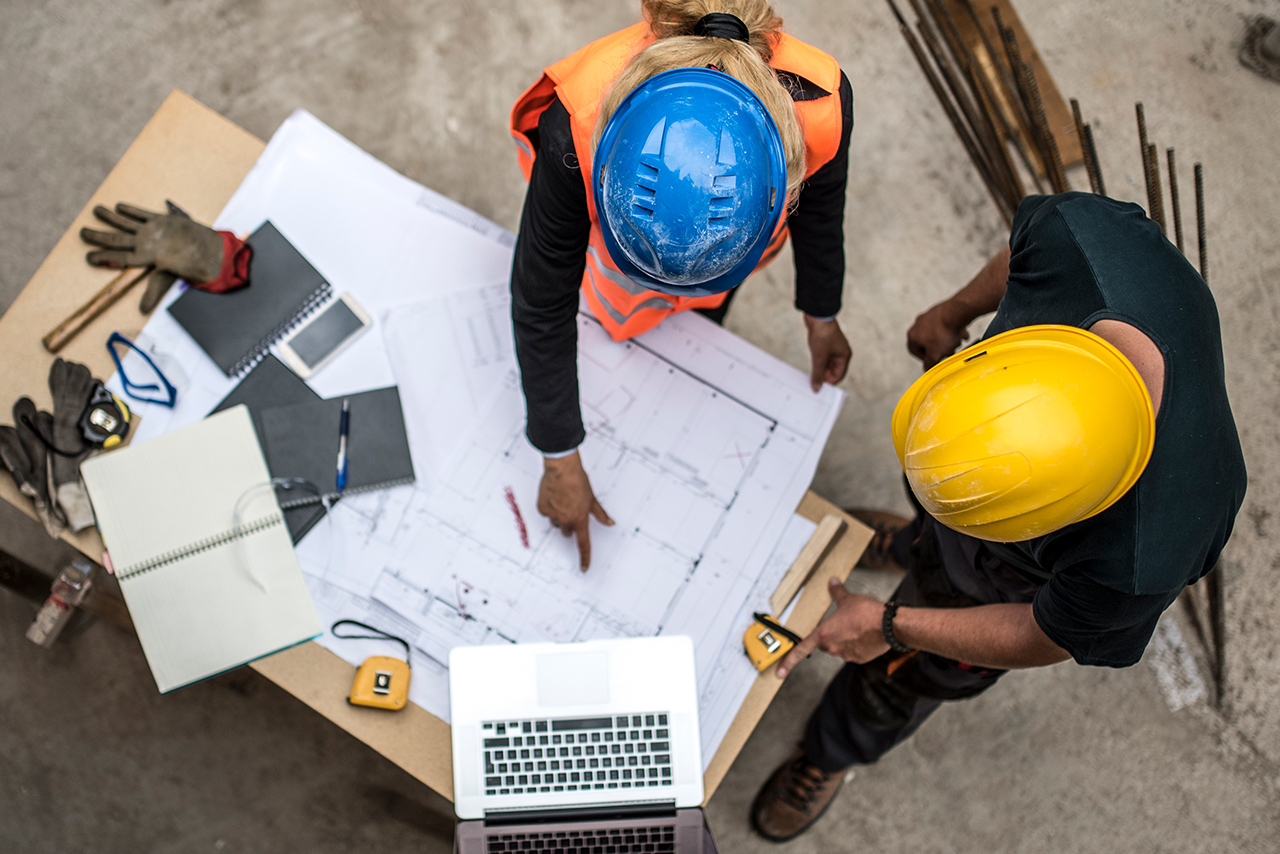 GS1 Standards im Bauwesen Bauarbeiter besprechen Baupläne auf einer Baustelle