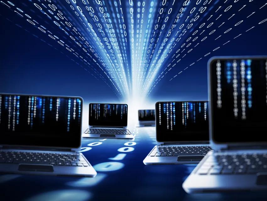 Laptops vor einem blauen Hintergrund an dem Binärcodes vorbei laufen als Symbolisierung eines Netzwerks
