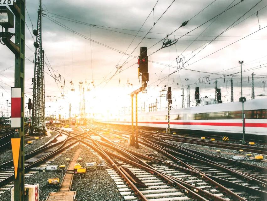 Gleise und Gleiskreuzungen vor Bahnhof mit vorbeifahrenden Zug