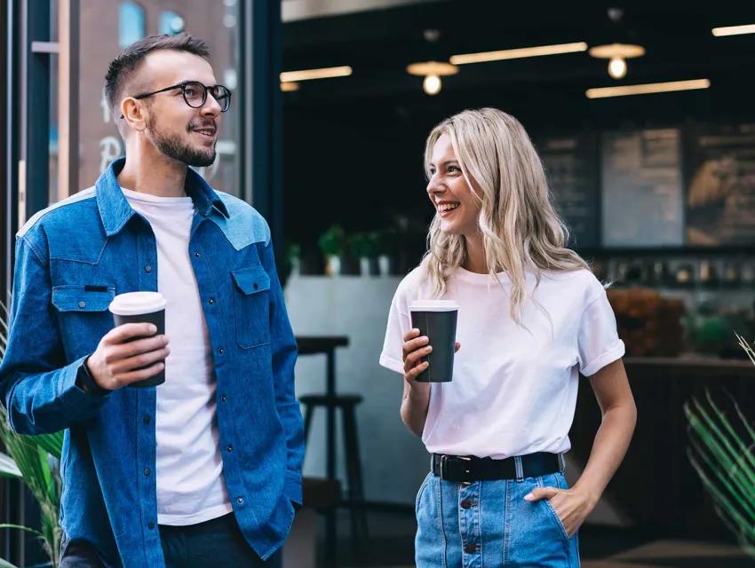 Mann und Frau vor einem Café halten Mehrweg-to-go Becher in der Hand