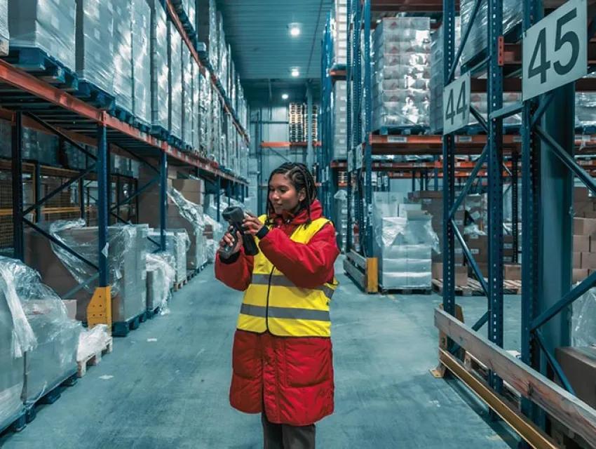 Mitarbeiterin im Lager scannt Produkte mit Strichcode-Scanner