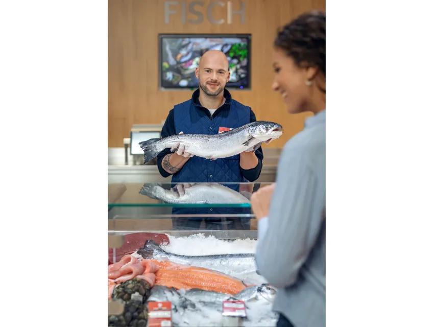 Foto eines Verkäufers mit einem Fisch in den Händen