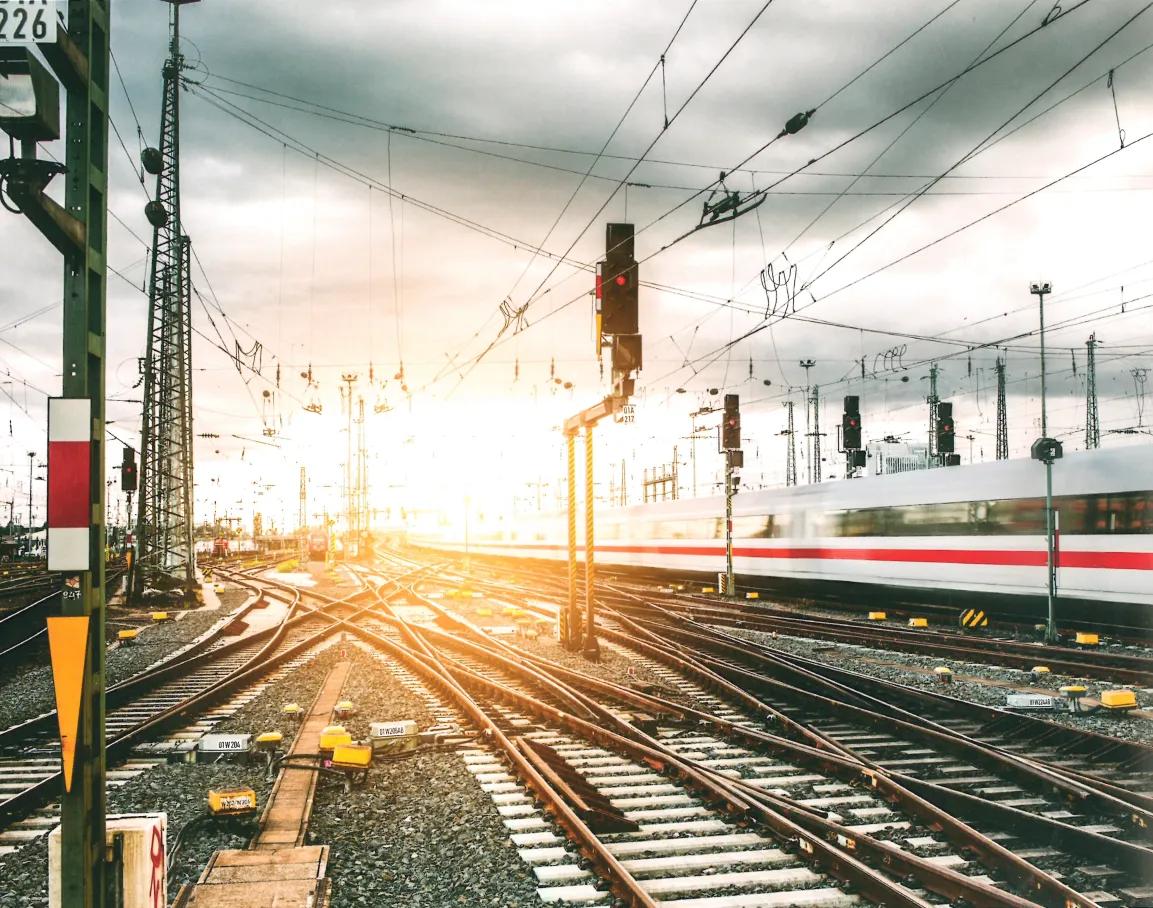 Gleise und Gleiskreuzungen vor Bahnhof mit vorbeifahrenden Zug