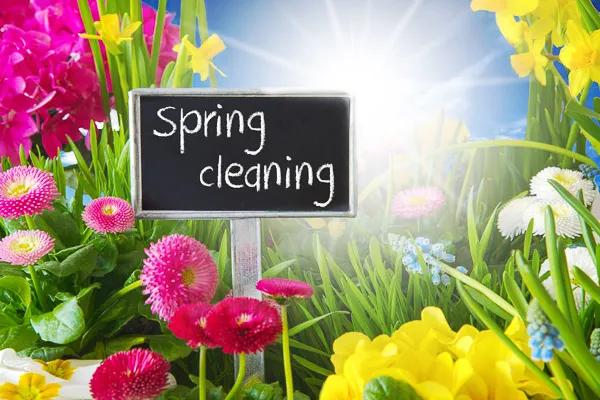 Foto einer Blumenwiese mit einem Schild, auf dem "Spring Cleaning", "Frühjahrsputz" steht