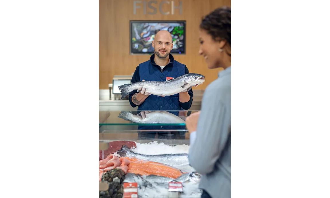 Foto eines Verkäufers mit einem Fisch in den Händen