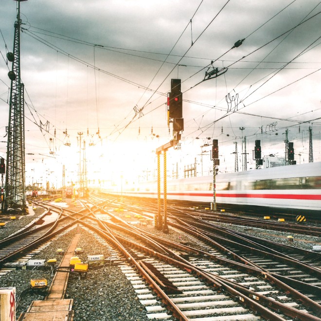 Gleise und Gleiskreuzungen vor Bahnhof mit vorbeifahrenden Zug