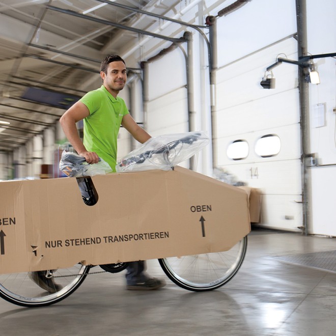 Logwin Mitarbeiter schiebt ein verpacktes Fahrrad